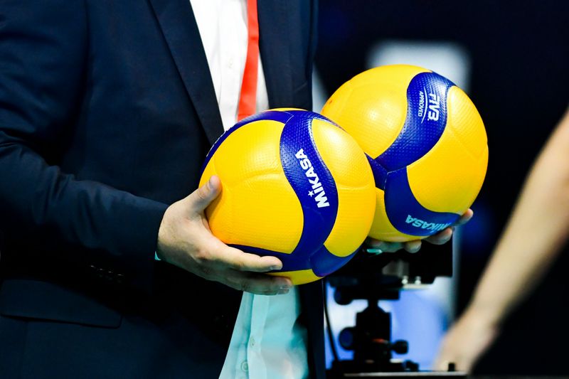 Man in a Blue Suit Holding a Yellow and Blue Volleyball